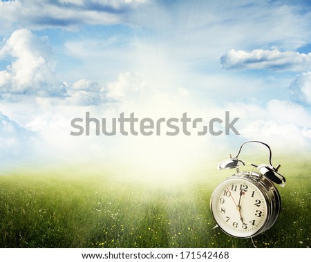 Alarm clock in sunlit spring field
