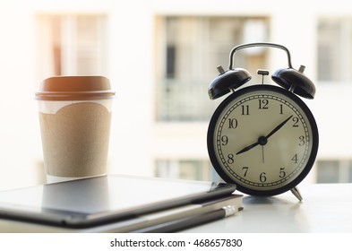 Alarm Clock, Tablet Computer, Paper Note Book And Coffee Cup On Wooden Desk By The Window In Morning Light. Overtime Working Concept. Part Time Job, Home Office, Working At Home.