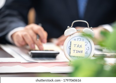 Alarm clock with tax time note and Businessmen using calculators. - Shutterstock ID 1797060616