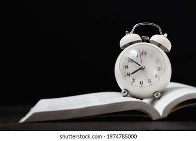 An Alarm Clock That Is Placed On A Textbook During The Summer Semester.