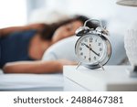 Alarm, clock and woman sleeping in bed with depression, tired or anemia and low energy or fatigue at home. Time, late and person dreaming, relax or lying with risk of iron deficiency or hypersomnia
