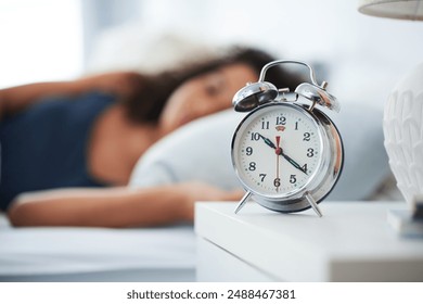 Alarm, clock and woman sleeping in bed with depression, tired or anemia and low energy or fatigue at home. Time, late and person dreaming, relax or lying with risk of iron deficiency or hypersomnia