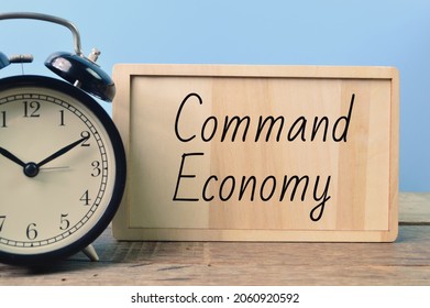 Alarm Clock And Wooden Board Written With COMMAND ECONOMY