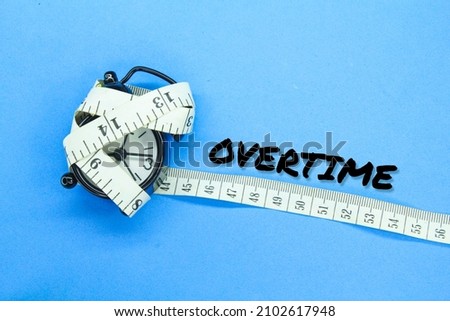 the alarm clock is wrapped with measuring tape with the word overtime