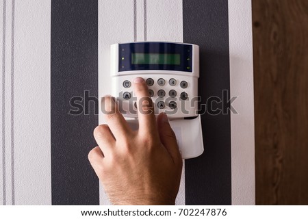 Alarm panel. Protection of the apartment and the house. The house is protected. A man's hand puts a siglanizuyu on the remote control