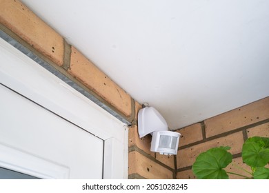 Alarm PIR sensor located by the front door of a house, inside a porch. - Shutterstock ID 2051028245