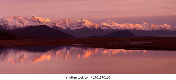 Alaska Coastal Mountain Range Reflection - The coastal mountain range across the Lynn Canal with alpenglow at sunset is reflected in a pool of water in the Chillkat Valley. Haines, Alaska. - Powered by Shutterstock