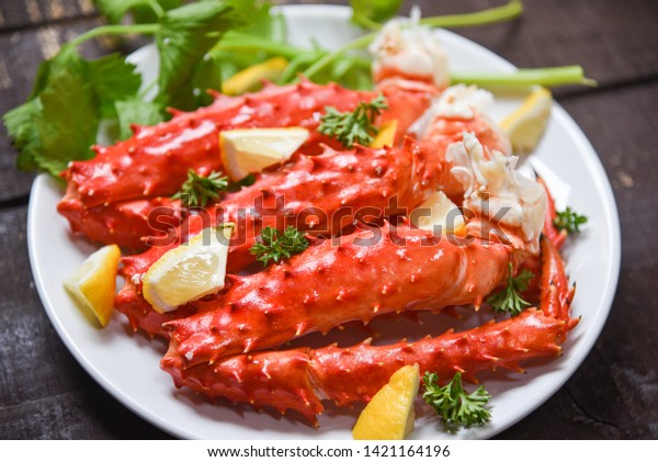 Alaskan King Crab\
Legs cooked seafood with lemon spices on white plate in the wooden\
table / red crab\
hokkaido