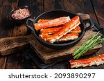 Alaskan King Crab legs Phalanx in a pan with herbs. Dark wooden background. Top view