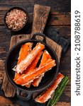 Alaskan King Crab legs Phalanx in a pan with herbs. Dark wooden background. Top view