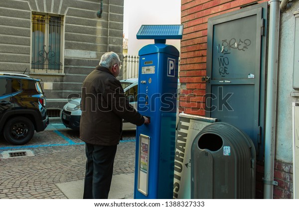 Alba, Cuneo / Italy
03-11-2019: 	Old man with hearing aid, get the ticket for paid car
parking in Italy.