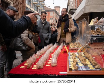 Alba, Italy - November 10, 2019: Truffle seller and his stall with white truffles, with potential buyers, on a street in Alba
