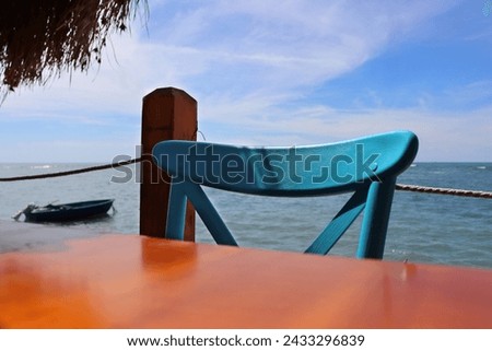 Dürres, Albania - September, 3rd, 2022: Spectacular view to the Adriatic sea from 2 the Kitarrat Arome Deti restaurant. Beautiful wooden retro chair hand painted turquoise.   Hot summer day.