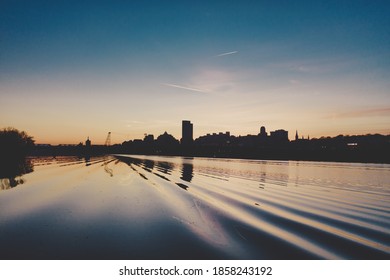 Albany NY Skyline At Dusk Seen From The Hudson River Over The Wake Of A Passing Boat