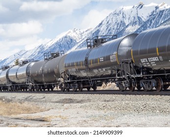 Alberta, Canada, April 16, 2022; A medium view of a train of empty ( no placard ) crude oil cars passing through Canmore on the CP Rail tracks with the Canadian Rocky Mountains in the background