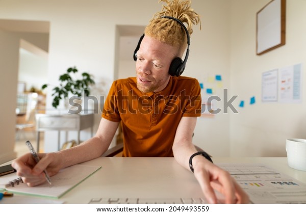 Albino african american\
man working from home making video call. remote working using\
technology at home.