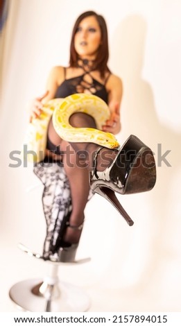albino moluro python on legs of dark goth brunette girl with high heels fetish. High quality photo