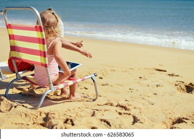 Albufeira, Portugal - 10 October, 2016: Child Holding In Hands Apple Ipad 2 Tablet Computer On Beach Outdoors Background. Vacation Relaxation Closeup Shot. Mobility E-reader, Smart Pad On Chair