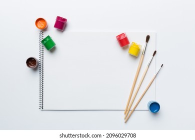 Album pages and paints, pencils, brush on a colored background. Top view with empty space. workplace for creativity. home teaching concept drawing. - Powered by Shutterstock