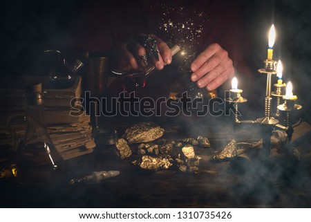 Alchemist is working at his magic table and producing a gold ore from a stones.