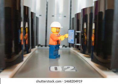 Alcobendas, Spain July 20, 2019: Male Technician Working In A Corridor Of A Data Processing Center, Studio Shot Of Lego Minifigure Man. Legos Are A Popular Line Of Plastic Construction Toys.