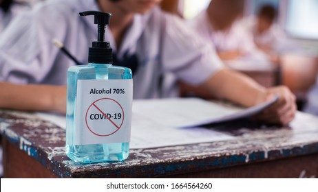 Alcohol 70%  Sanitizer Standing On The Table For Protect Corona Virus Or Covid-19 With Students Doing Exam  In Classroom Of School With Stress.16:9 Style