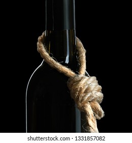 Alcohol Abuse Concept. A Bottle Of A Vine With A Rope Loop On The Neck Symbolizes That Alcoholism Is Suicide Isolated On The Black Background. Square Photo Format.                               