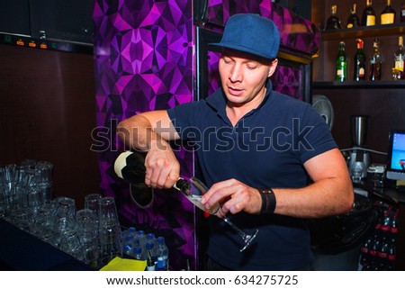 Alcohol cocktail on the bar. Bartender prepares an alcoholic cocktail. The bartender pours the champagne from the bottle into the glass. Barman at work in night club during night party