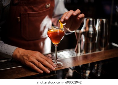 alcohol drinks, people and luxury concept - bartender with glass and lemon peel preparing cocktail at bar - Powered by Shutterstock