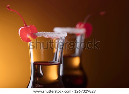 Alcohol layered shot cocktail garnished with cherry and sugar. 