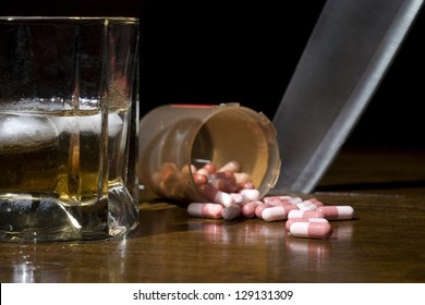 Alcohol and pills in the foreground with a knife sticking out the table in the background