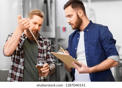 alcohol production, manufacture, business and people concept - male brewers with pipette and clipboard testing craft beer at brewery - Powered by Shutterstock