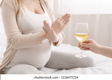 Alcohol prohibited. Pregnant woman with crossed hands refusing to drink wine, making denying gesture to glass, copy space