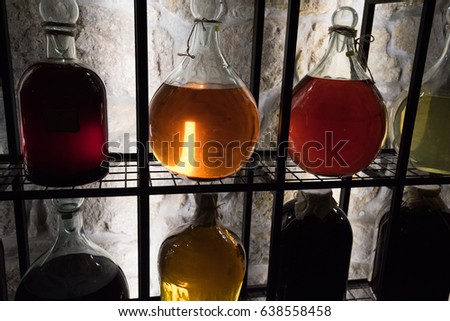 Alcohol in vintage large bottles is placed on decorative racks with darkened illumination.