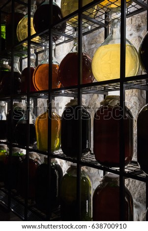 Alcohol in vintage large bottles is placed on decorative racks with darkened illumination.
