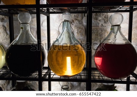 Alcohol in vintage large bottles is placed on decorative racks with vibrant illumination.
