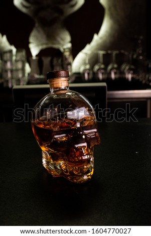 Alcohol, whiskey in a bottle in the form of a skull on a black background.