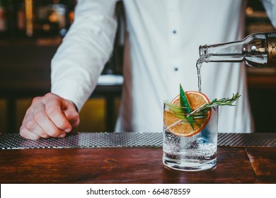 Alcoholic cocktail in bar, Bartender making gin cocktail with garnishes 