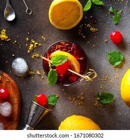 Alcoholic Cocktail With Cherry, Lemon And Ice On A Black Background, Top View. Cold Refreshing Drink And Ingredients For Making On The Table.