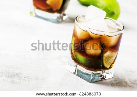Alcoholic cocktail with cola, lime, vodka and ice, selective focus