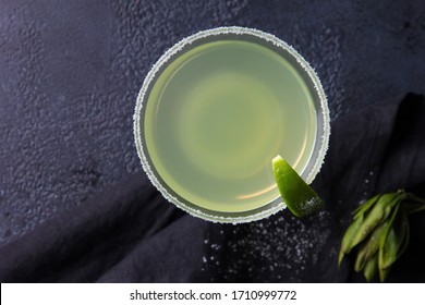 Alcoholic Daiquiri cocktail with salt and lime on a dark grey background. Bar menu. Green beverage. Top view, flatlay. Background image, copy space