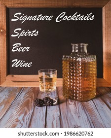 An Alcoholic Drink With Blackberries In Front Of A Chalkboard Sign.  Advertising Different Types Of Drinks.