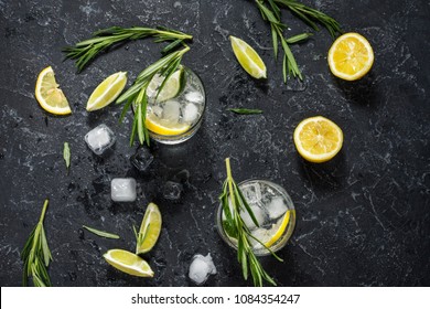 Alcoholic Drink Gin Tonic Cocktail With Lemon, Rosemary And Ice On Stone Table. Top View