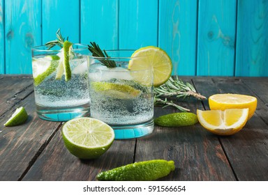 Alcoholic drink gin tonic cocktail with lemon, rosemary and ice on rustic wooden table, copy space - Shutterstock ID 591566654