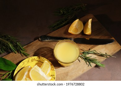 Alcoholic drink limoncello. Shot glass of Italian lemon liqour decorated rosemary, fresh lemons and limoncello decanter on table.