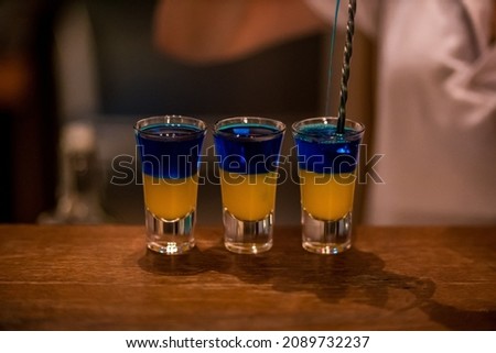 Alcoholic drinks in glass stacks on a wooden table. Blue curacao and lemon liqueurs.