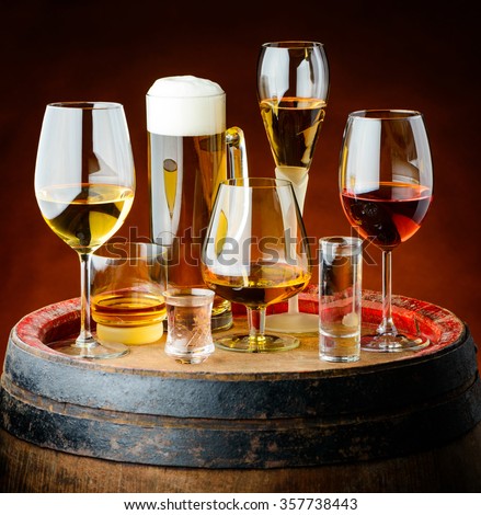 Alcoholic drinks in glasses on a wooden barrel in a cellar.