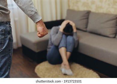 The alcoholic husband beats his wife with his fist. Zhenzhina covers herself with her hands. Violence in family - Shutterstock ID 1913723101