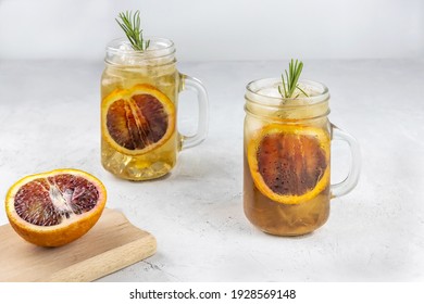 Alcoholic Kombucha Cocktail With A Slice Of Red Orange, Ice And A Sprig Of Rosemary