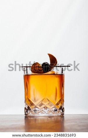 Alcoholic Old Fashioned Cocktail classic on the rocks garnish with orange peel and a cherry